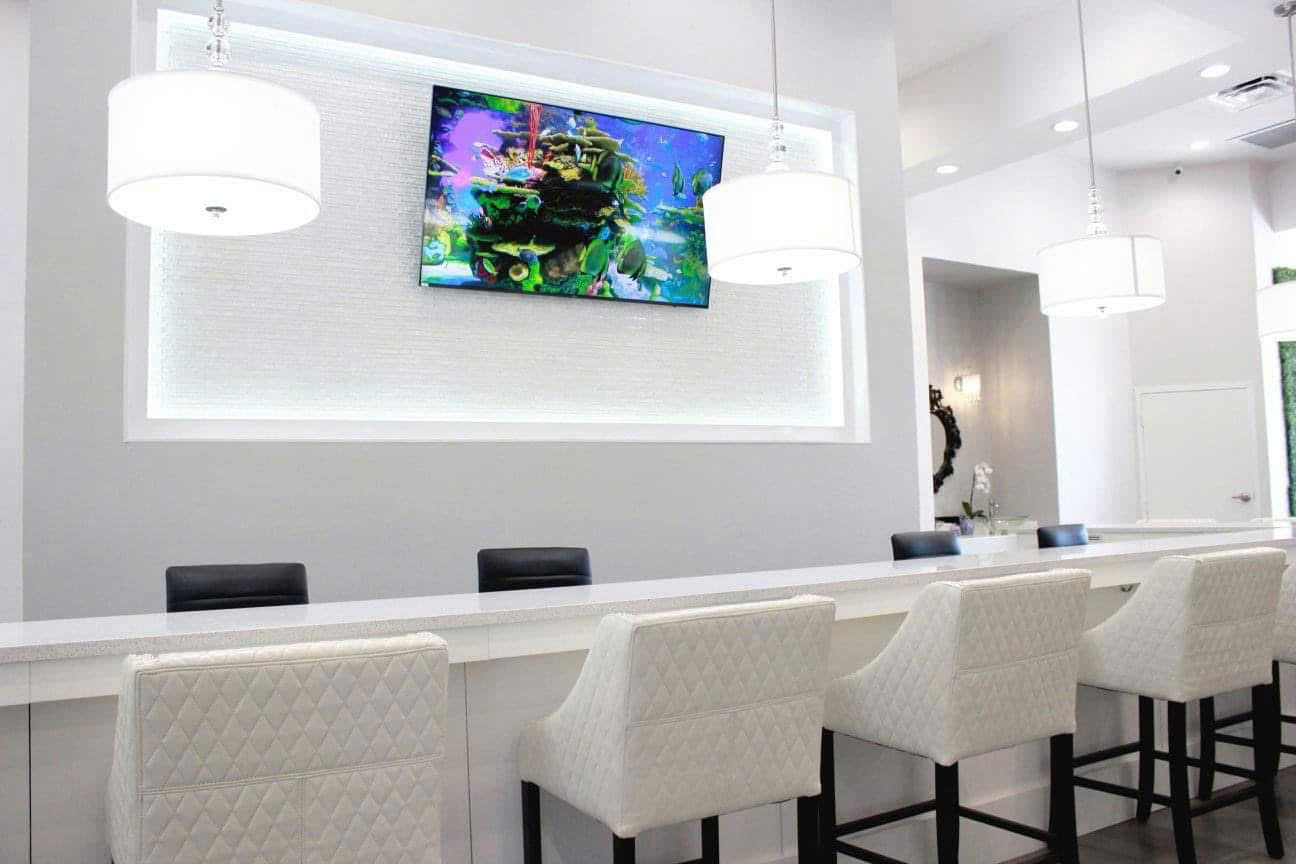 Manicure bar with white drum pendants and large tropical aquarium display