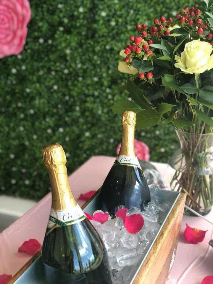 Complimentary champagne service with fresh florals against rose wall